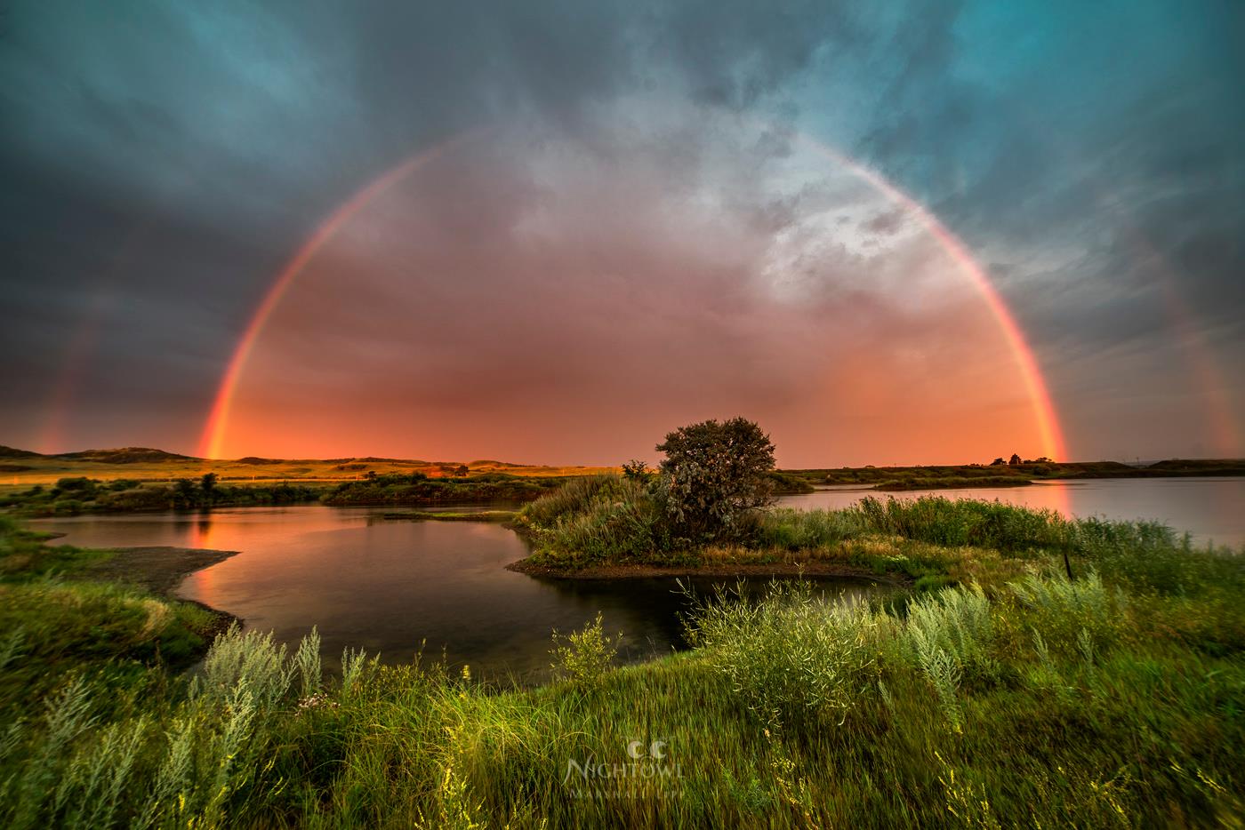 A rainbow over still prairie water